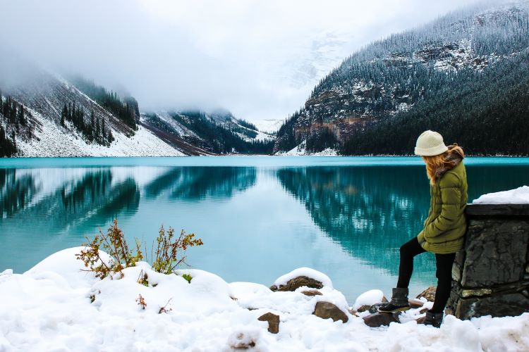 Mädchen macht Winterwanderung am blauen See in den kanadischen Rockies.
